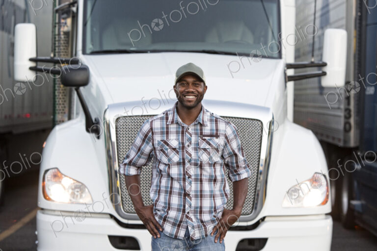 Black man truck driver near his truck parked in a parking lot at a truck stop
