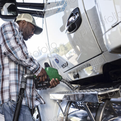 Black man truck driver putting diesel fuel in his truck at a truck stop. Black man truck driver putting diesel fuel in his truck at a truck stop.