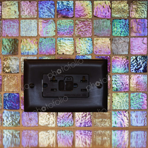 Black plug socket in colourful mosaic tile. Black plug socket in colourful mosaic tile.