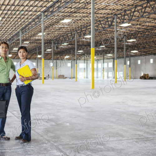Black woman and Asian woman standing inside of a brand new empty warehouse.