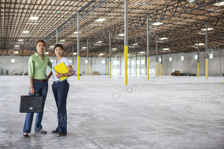 Black woman and Asian woman standing inside of a brand new empty warehouse.