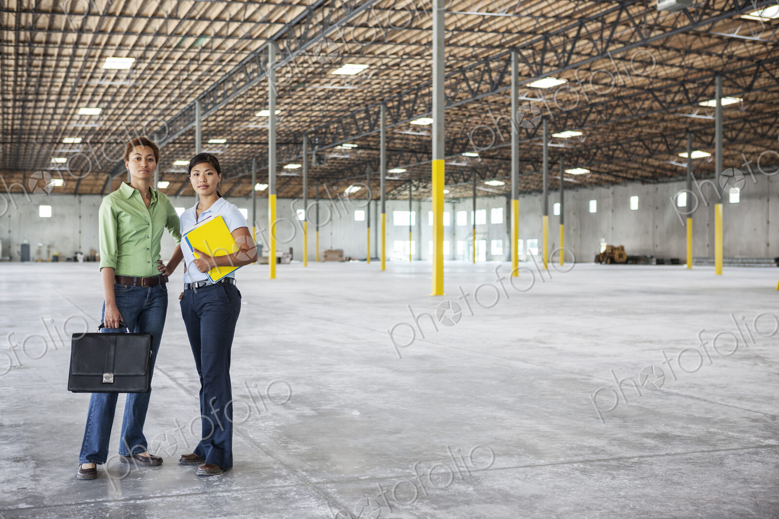 Black woman and Asian woman standing inside of a brand new empty warehouse.