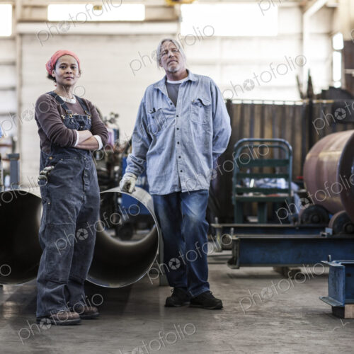 Black woman and caucasian male workers in a sheet metal factory.
