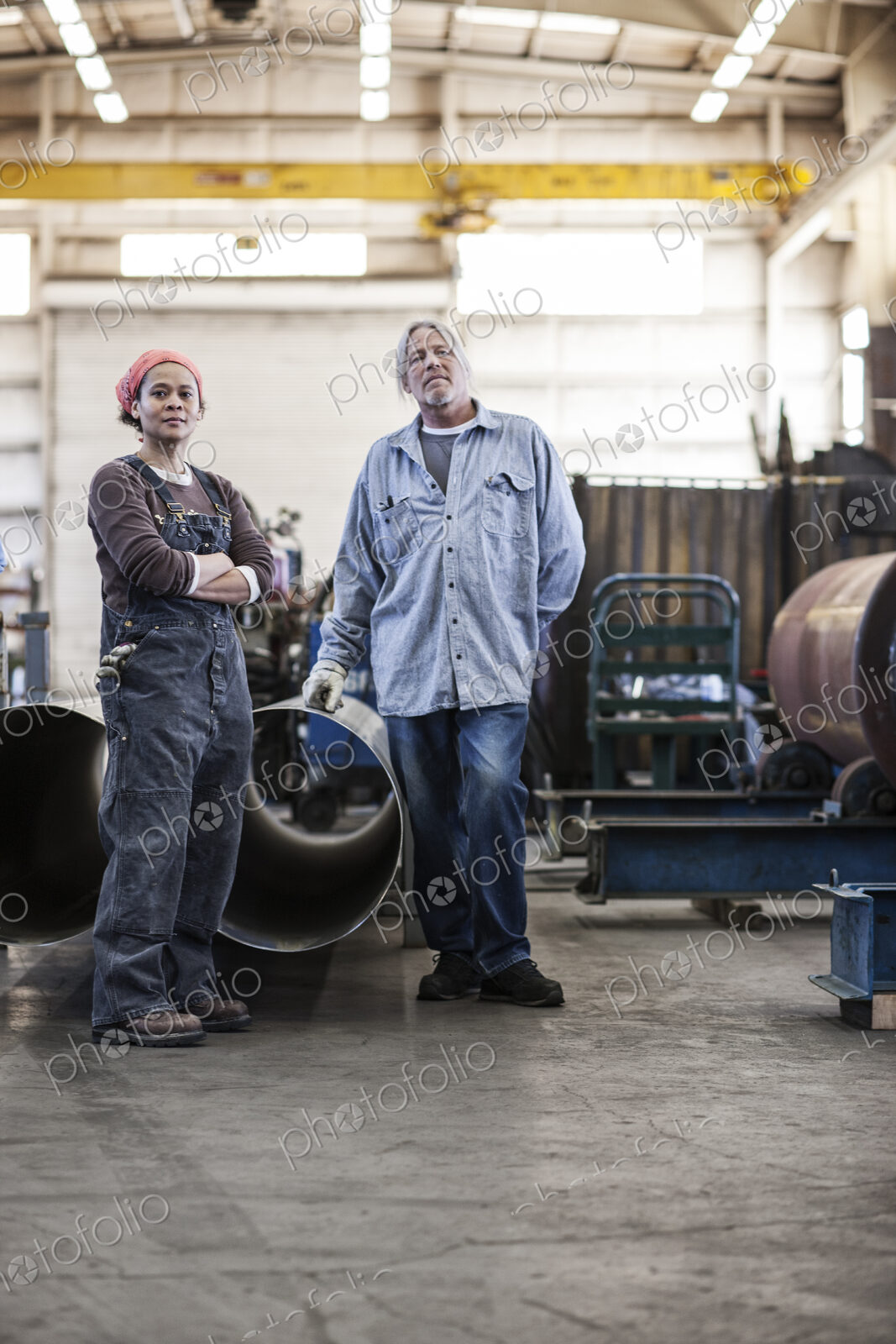 Black woman and caucasian male workers in a sheet metal factory.
