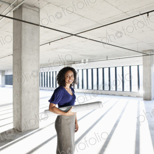 Black woman architect standing in a large empty raw office space.