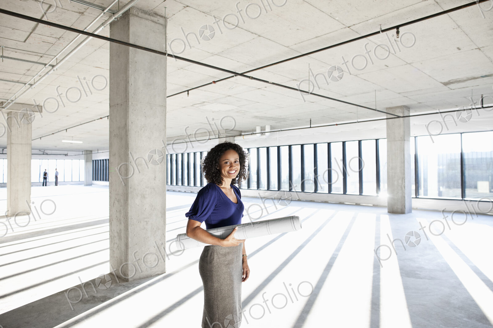 Black woman architect standing in a large empty raw office space.