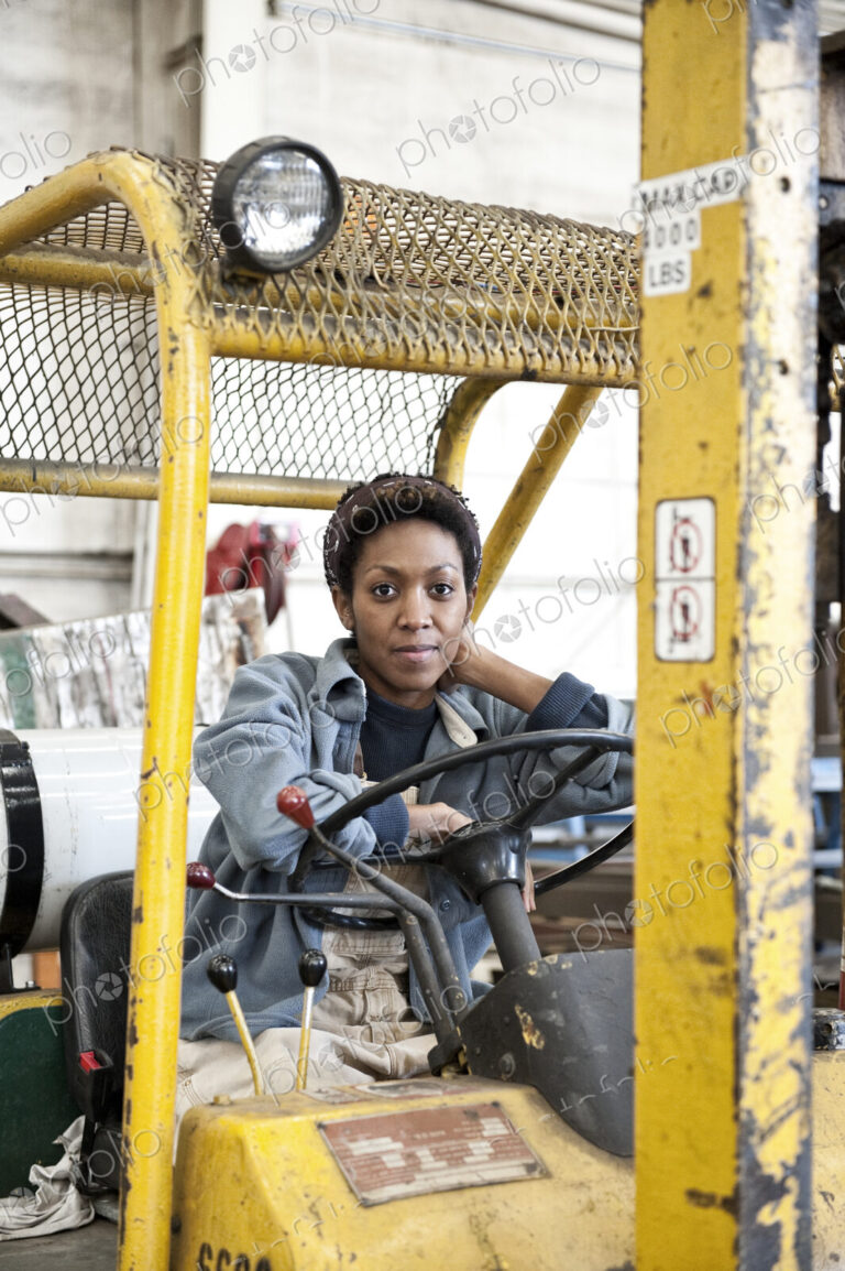 Black woman factory worker and a fork lift in a sheet metal factory.