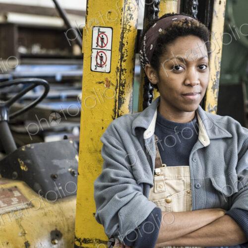 Black woman factory worker and a fork lift in a sheet metal factory. Black woman factory worker and a fork lift in a sheet metal factory.