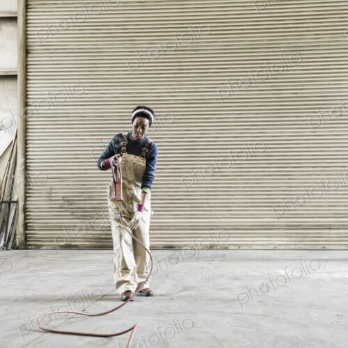 Black woman factory worker gathering tools together on the floor of a sheet metal factory.