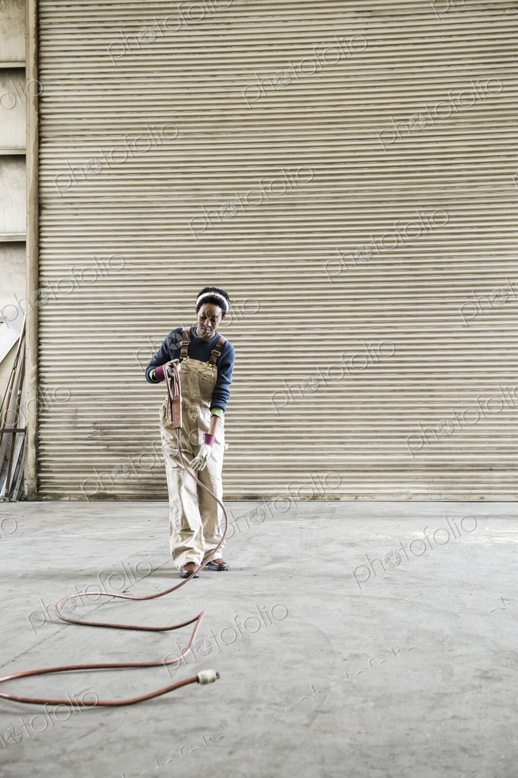 Black woman factory worker gathering tools together on the floor of a sheet metal factory.