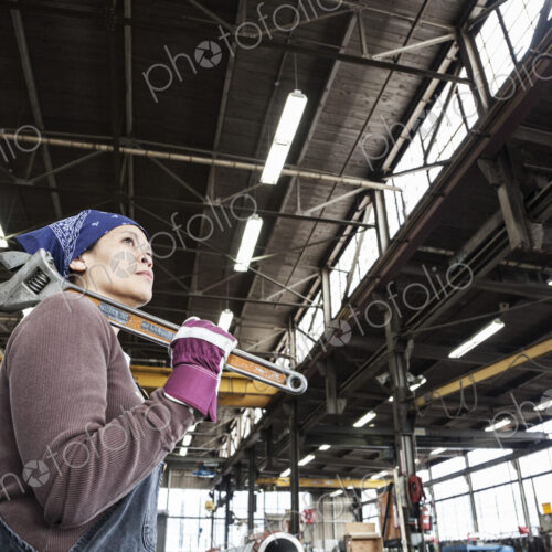 Black woman factory worker holding a large wrench in a sheet metal factory. Black woman factory worker holding a large wrench in a sheet metal factory.