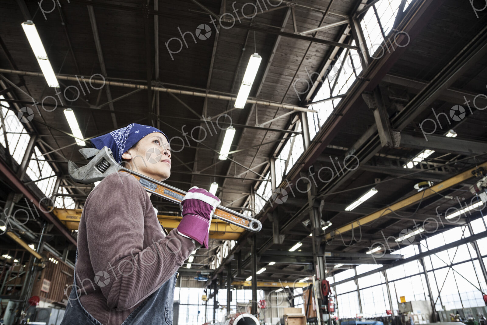 Black woman factory worker holding a large wrench in a sheet metal factory.