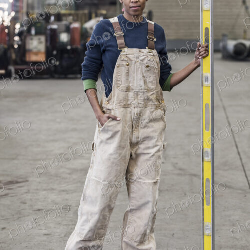 Black woman factory worker standing on the floor of a sheet metal factory.