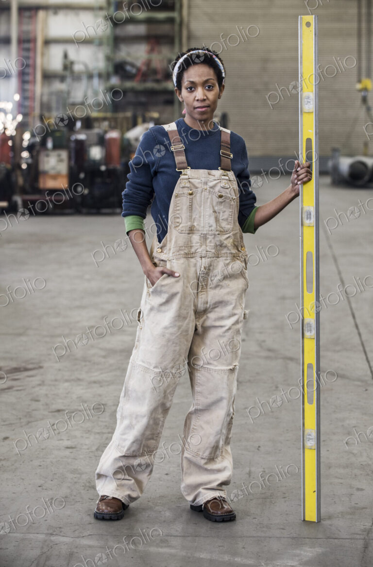 Black woman factory worker standing on the floor of a sheet metal factory.