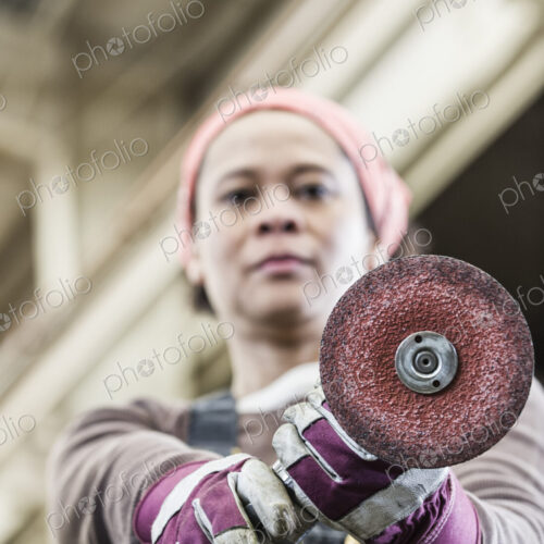 Black woman factory worker using a metal grinding tool in a sheet metal factory.