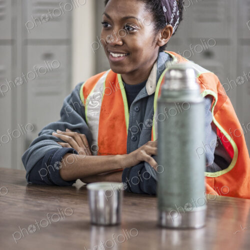 Black woman factory worker wearing a safety vest and taking a break in a factory break…