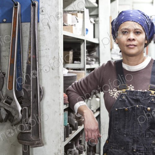 Black woman factory worker wearing coveralls in a large sheet metal factory. Black woman factory worker wearing coveralls in a large sheet metal factory.