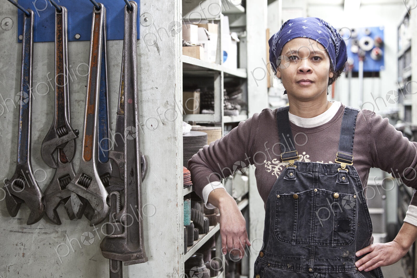 Black woman factory worker wearing coveralls in a large sheet metal factory.
