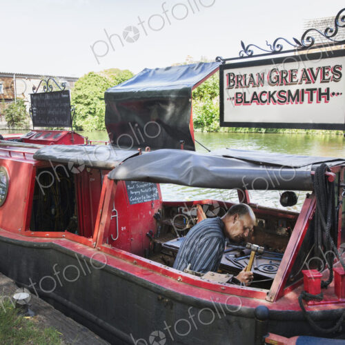 Blacksmith at work on his narrowboat moored on the canal.