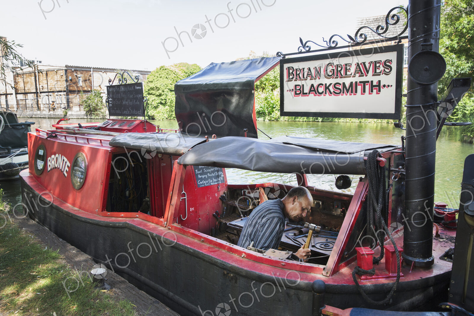 Blacksmith at work on his narrowboat moored on the canal.