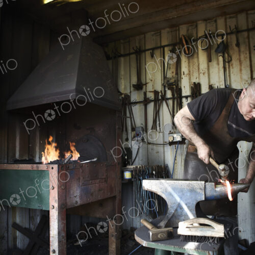 Blacksmith shaping a hot piece of iron on an anvil