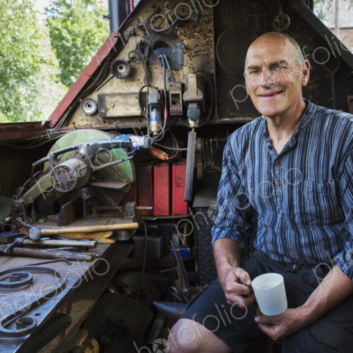 Blacksmith sitting on a working boat, a narrowboat on a waterway, holding a mug,… Blacksmith sitting on a working boat, a narrowboat on a waterway, holding a mug,…