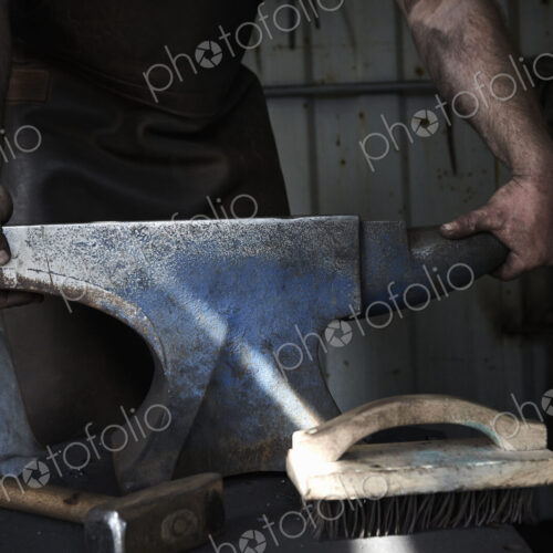 Blacksmith standing at an anvil in a traditional forge. Blacksmith standing at an anvil in a traditional forge.