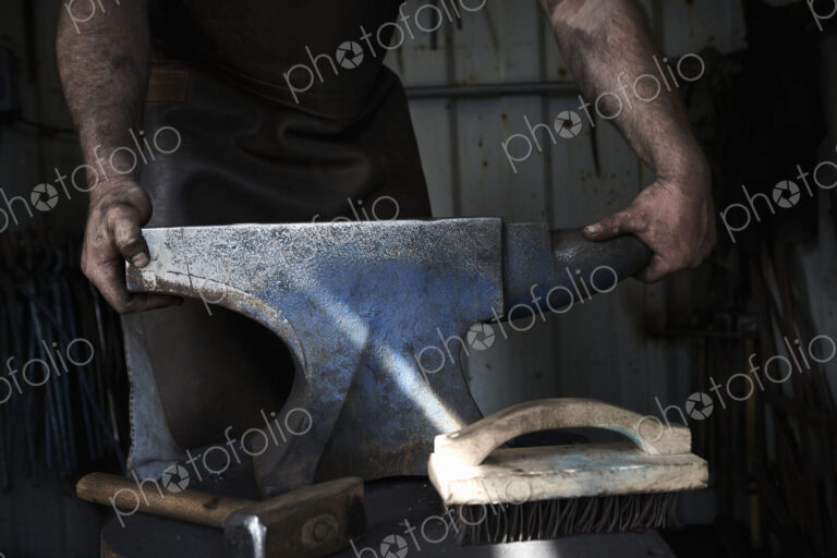 Blacksmith standing at an anvil in a traditional forge.