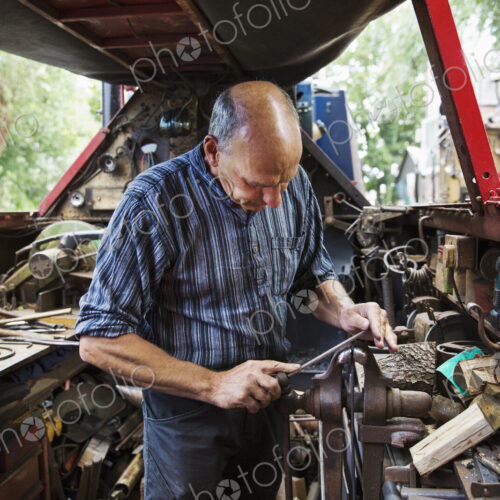 Blacksmith standing in his workshop, a floating forge on a narrowboat barge, working…