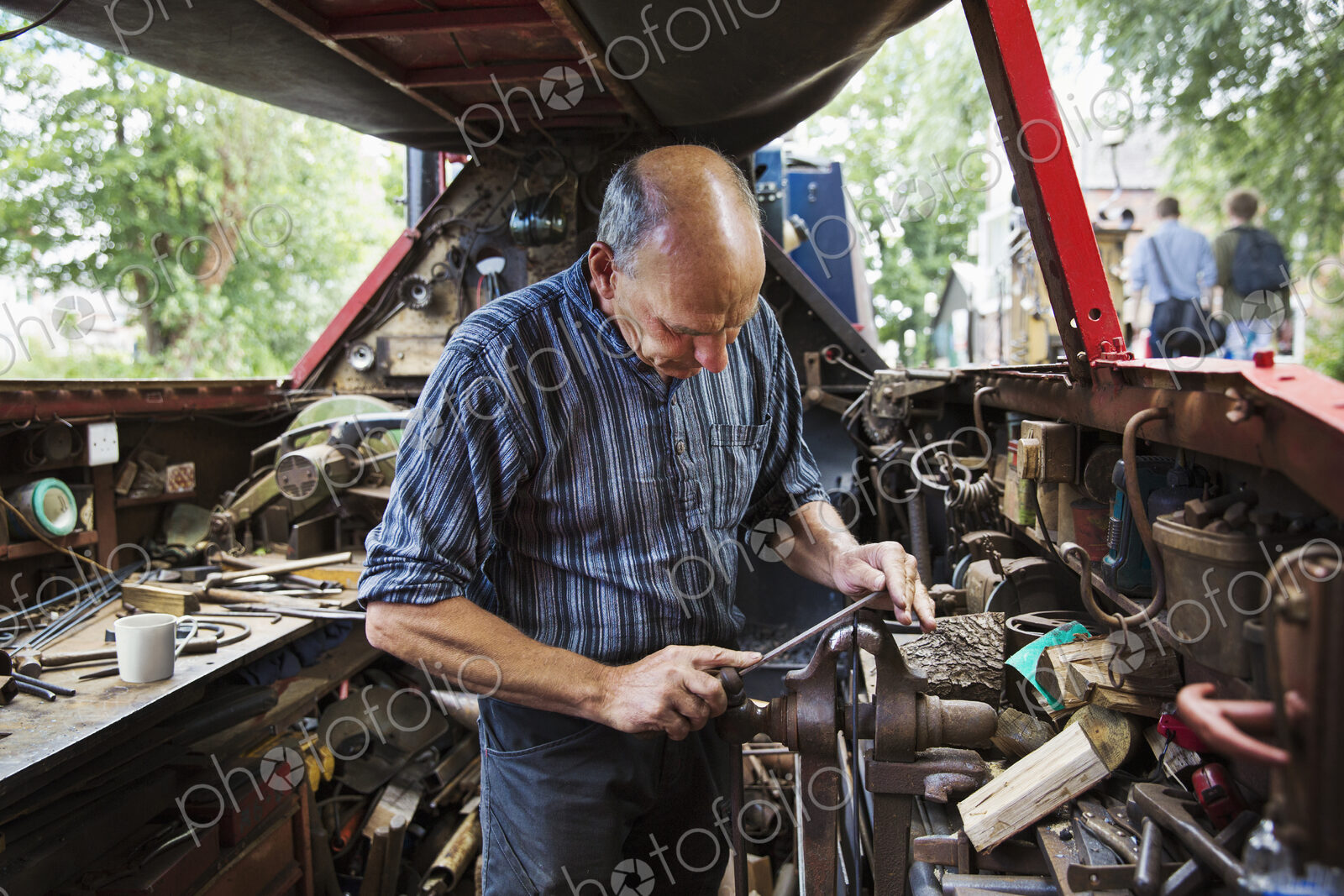 Blacksmith standing in his workshop, a floating forge on a narrowboat barge, working…