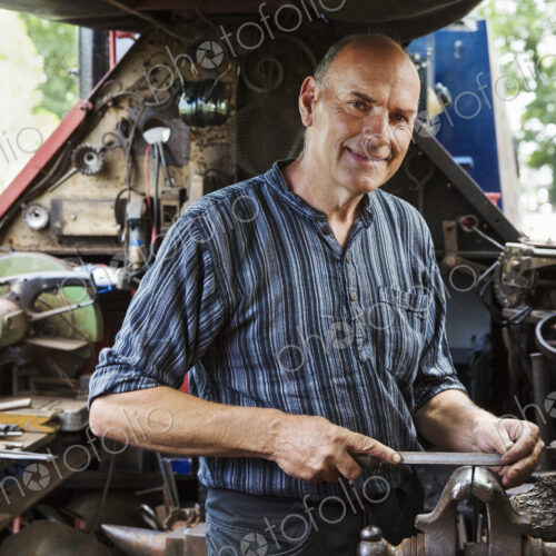 Blacksmith standing on a narrowboat barge in his workshop, holding a metal file.