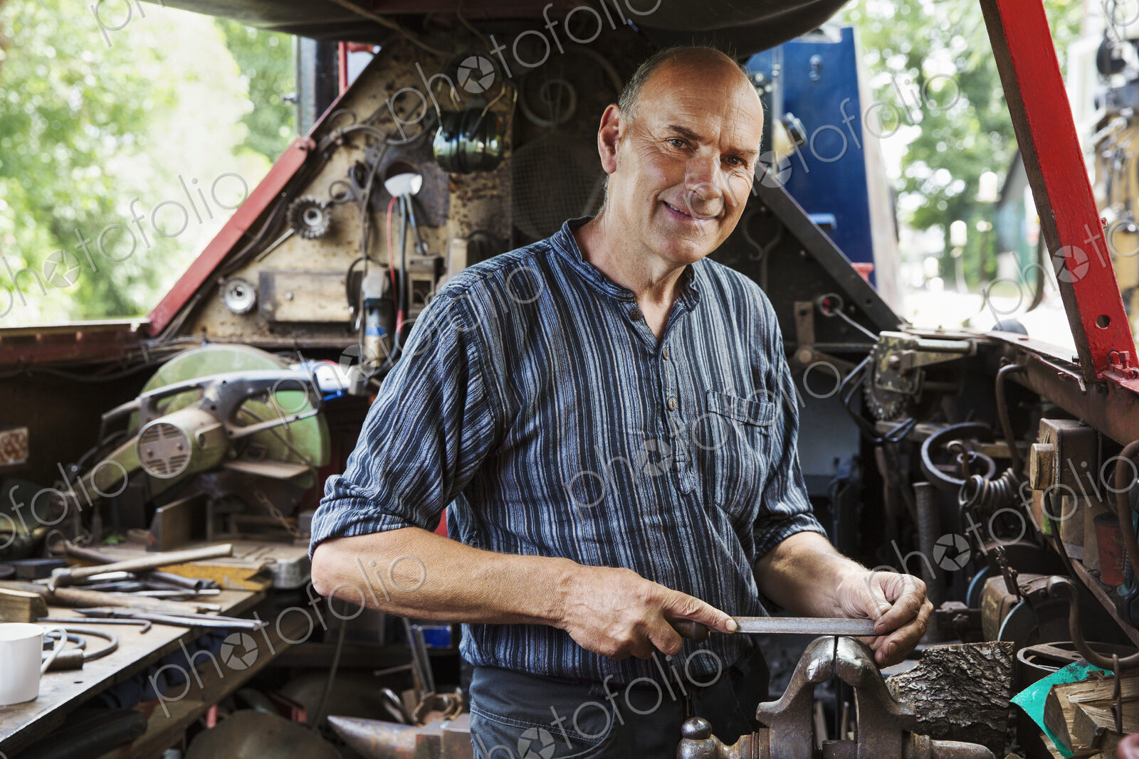 Blacksmith standing on a narrowboat barge in his workshop, holding a metal file.