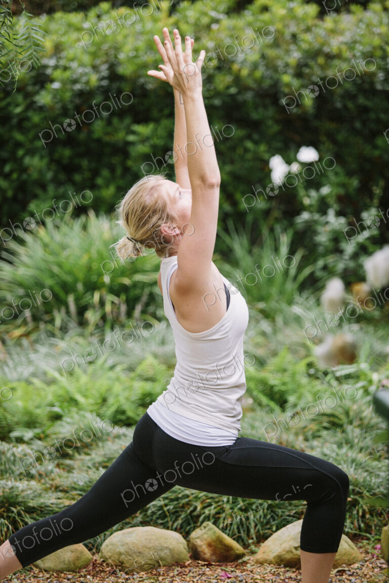 Blond woman doing yoga in a garden.