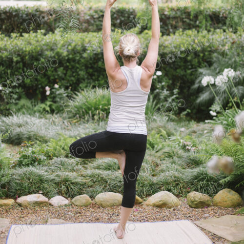 Blond woman doing yoga in a garden.