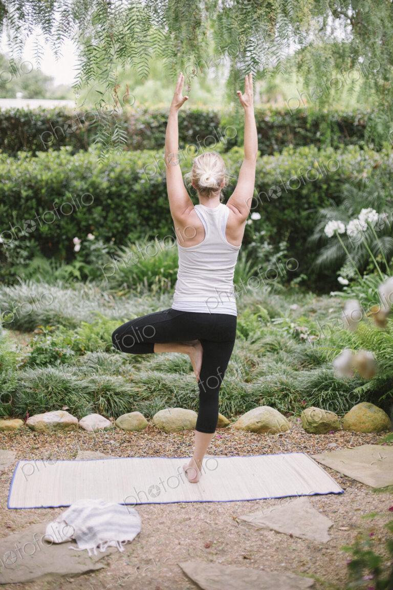 Blond woman doing yoga in a garden.