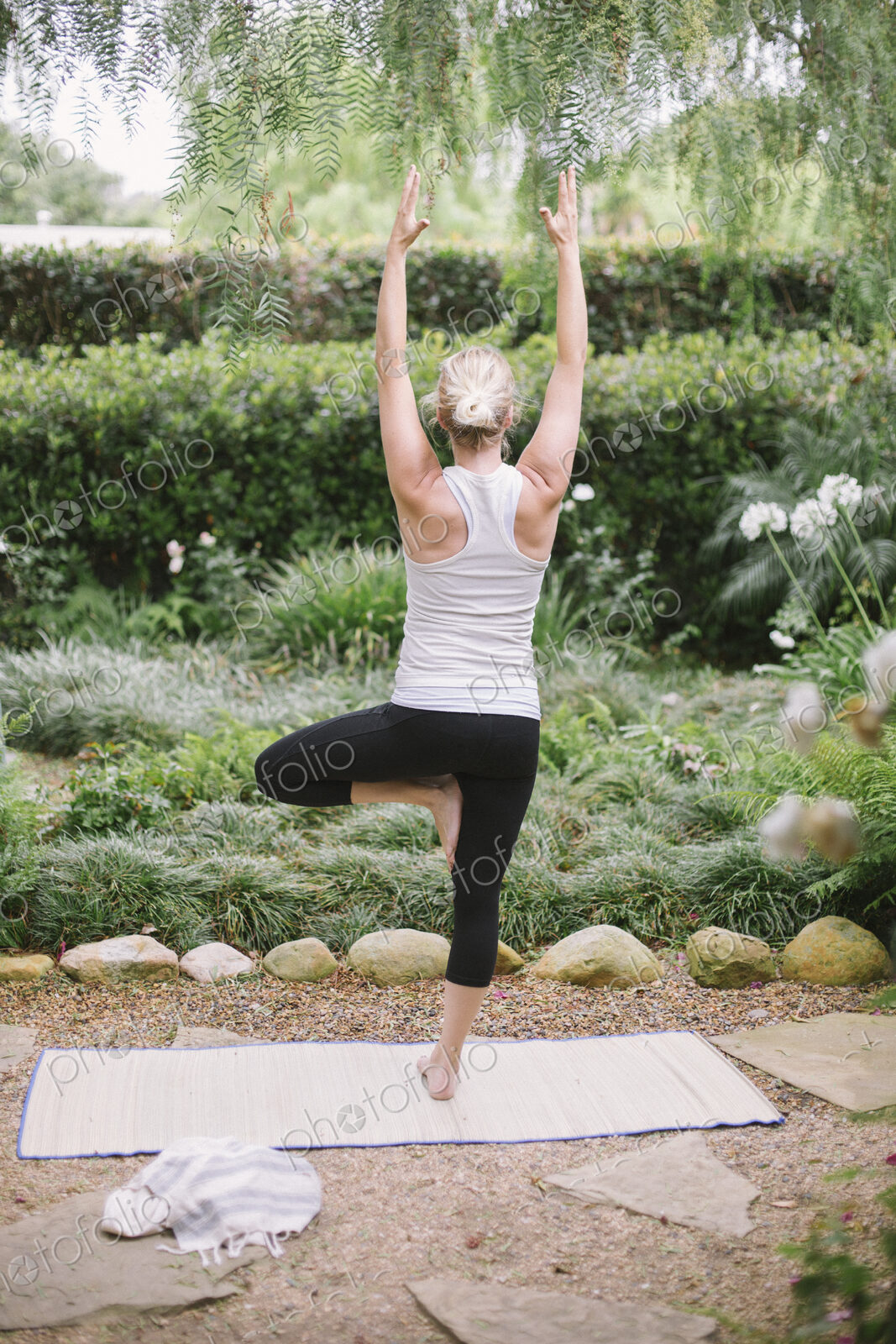 Blond woman doing yoga in a garden.