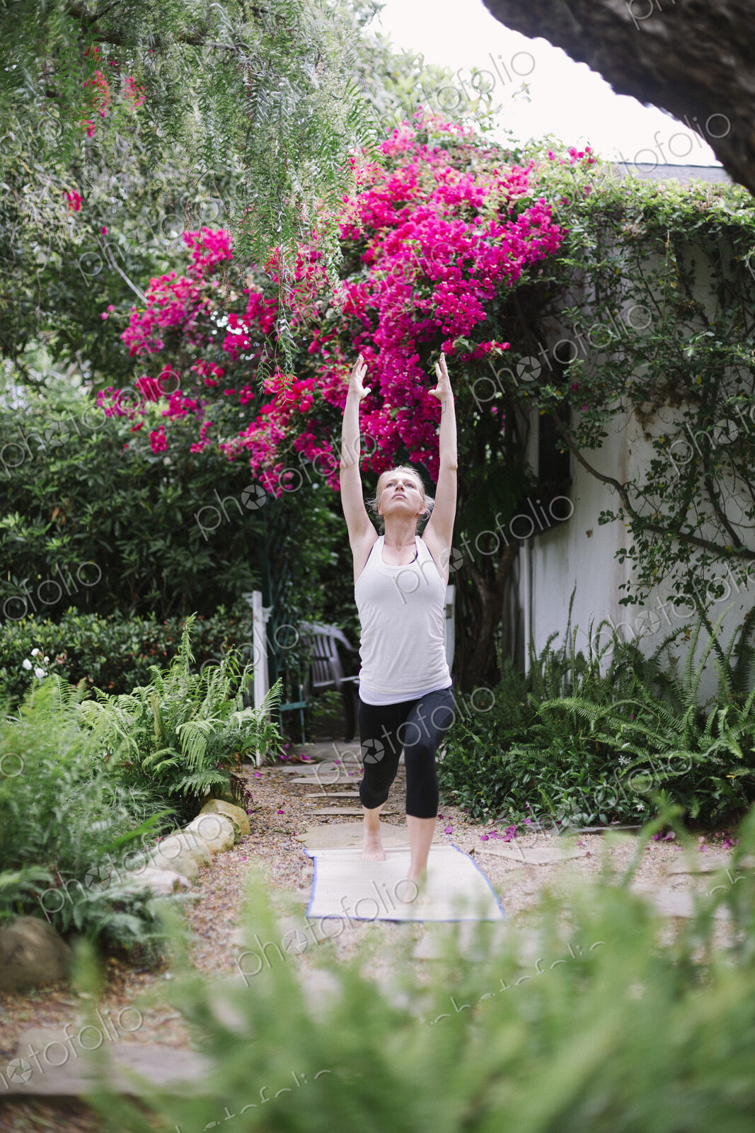 Blond woman doing yoga in a garden.
