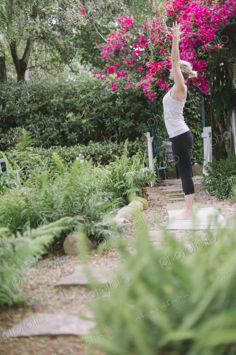 Blond woman doing yoga in a garden.