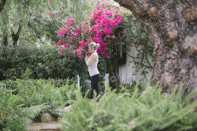 Blond woman doing yoga in a garden.
