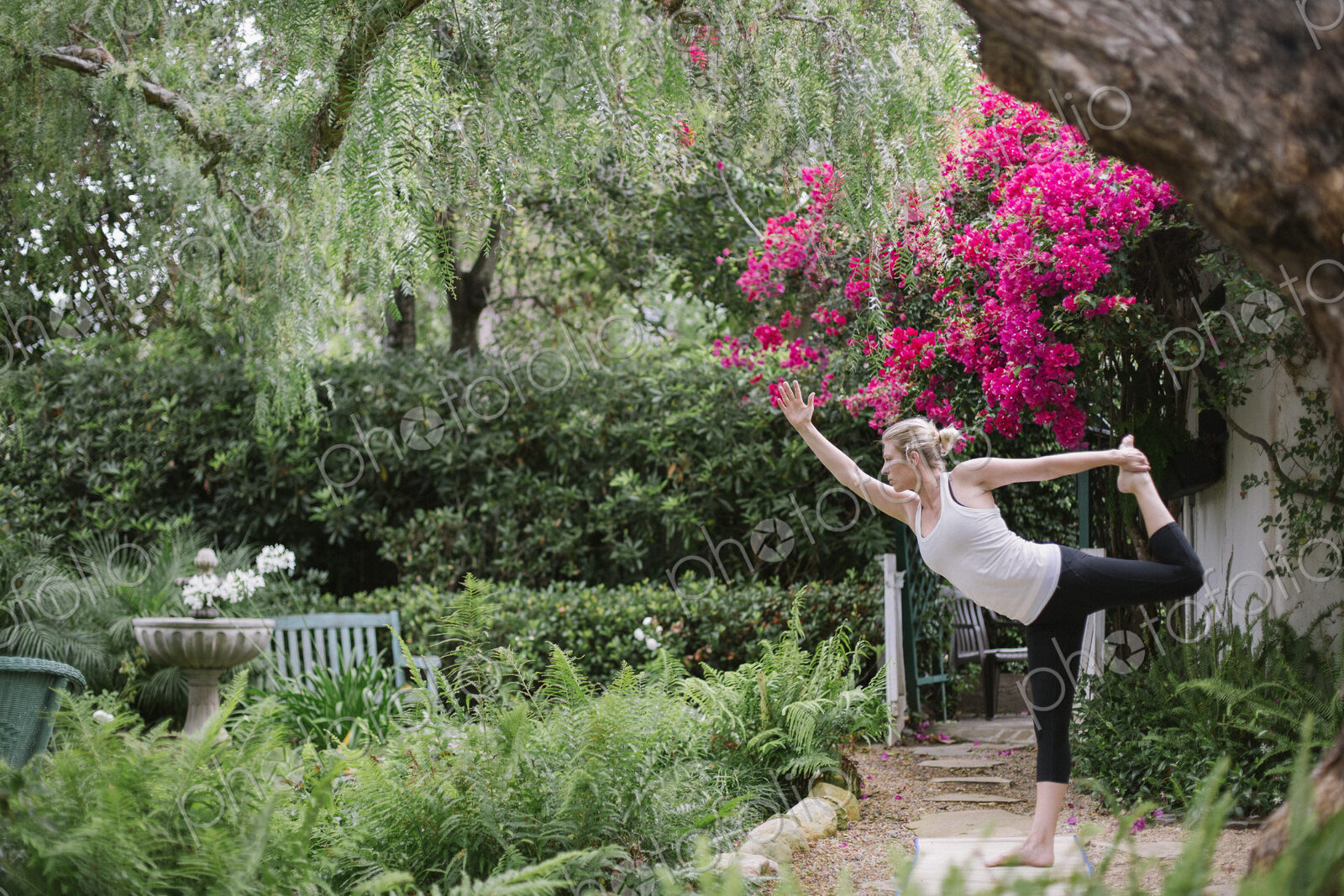 Blond woman doing yoga in a garden.