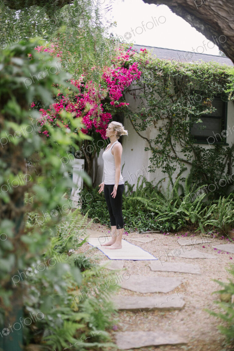 Blond woman doing yoga in a garden.