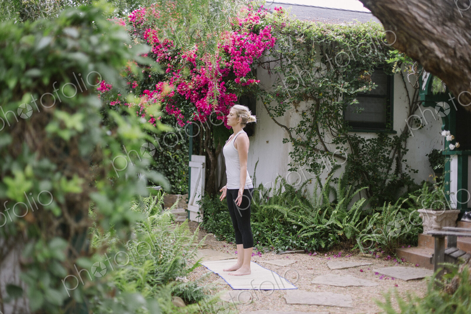Blond woman doing yoga in a garden.