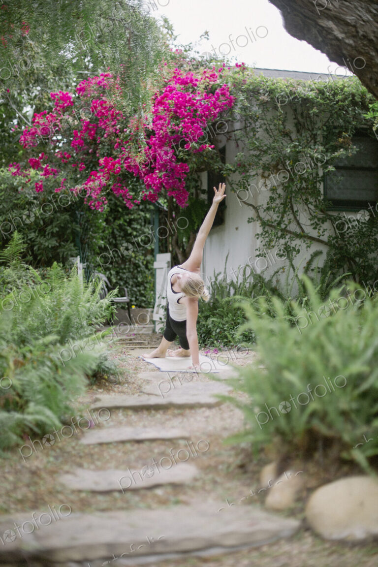 Blond woman doing yoga in a garden.