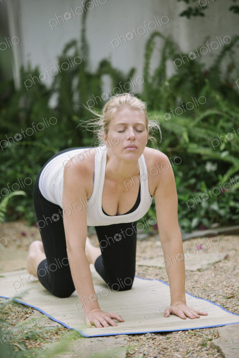 Blond woman doing yoga in a garden.