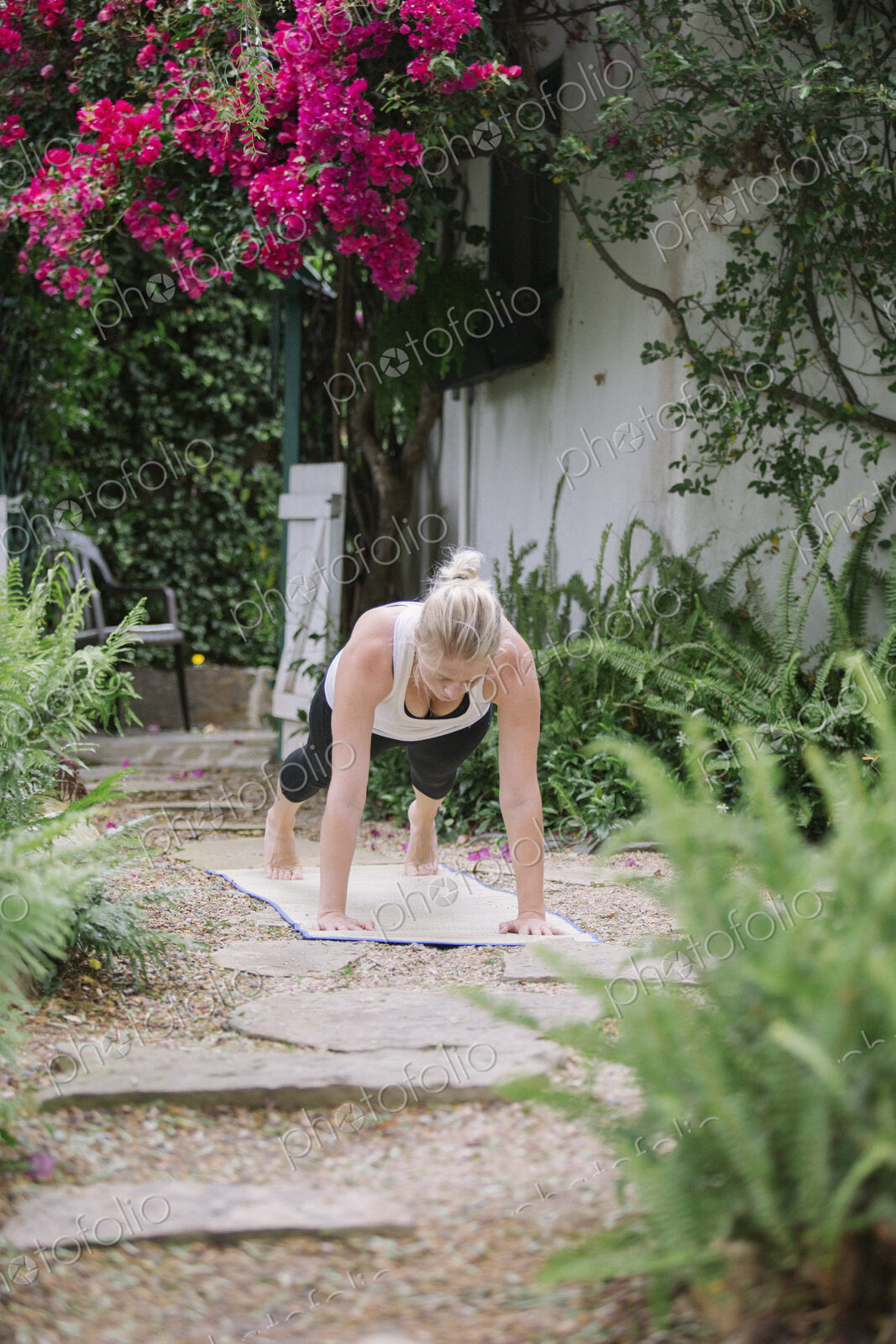 Blond woman doing yoga in a garden.