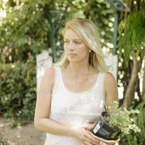 Blond woman in a garden, holding a plant pot. Blond woman in a garden, holding a plant pot.