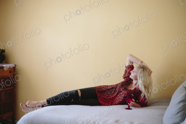 Blond woman reclining on a bed.