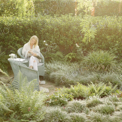 Blond woman sitting in a wicker chair in a garden, reading. Blond woman sitting in a wicker chair in a garden, reading.