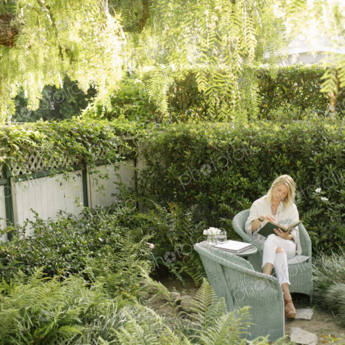 Blond woman sitting in a wicker chair in a garden, reading. Blond woman sitting in a wicker chair in a garden, reading.
