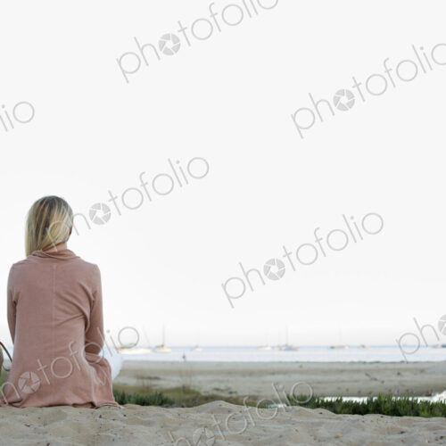 Blond woman sitting on a sandy beach. Blond woman sitting on a sandy beach.
